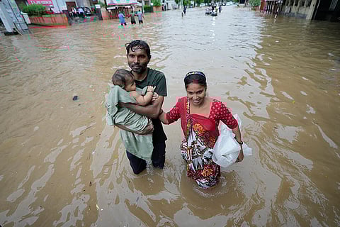 A couple with a child walk through a flooded road in Ahmedabad